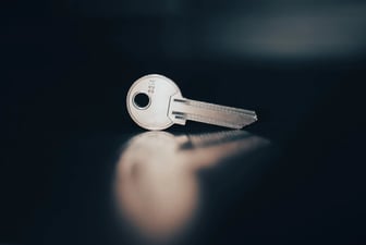 Ένα ασημένιο κλειδί όρθιο σε σκούρα γυαλιστερή επιφάνεια, λογοπαίγνιο για τις σωστές λέξεις-κλειδιά
